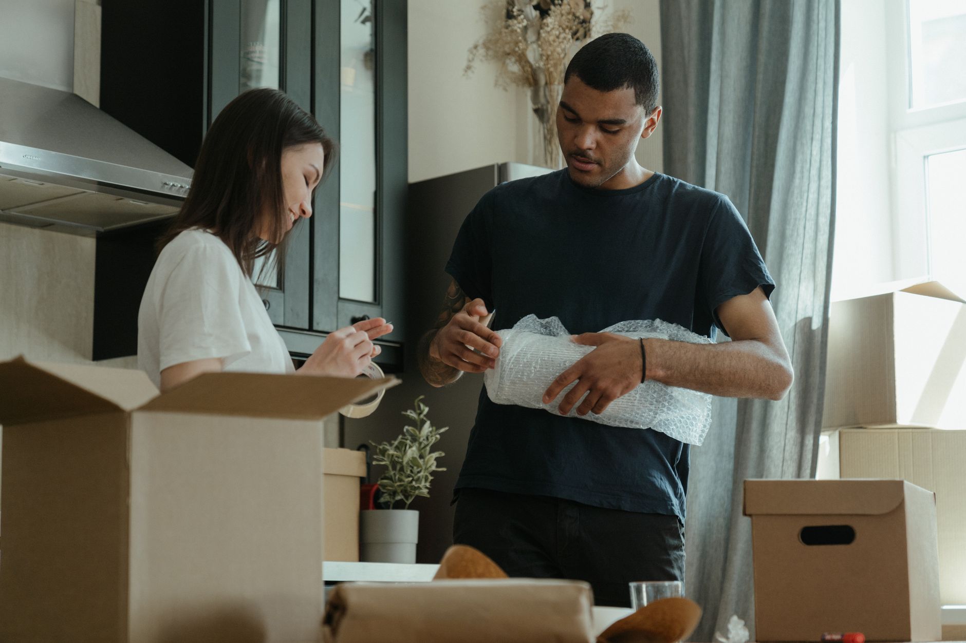 A young couple unpacks moving boxes in the kitchen of a new apartment